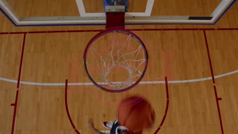 Toma-Aérea-En-ángulo-Alto-De-Un-Jugador-De-Baloncesto-Universitario-Afroamericano-Practicando-Mates-Solo-En-Una-Cancha-Cubierta.-Imágenes-En-Cámara-Lenta,-4k,-UHD,-50-Fps,-Sin-Editar